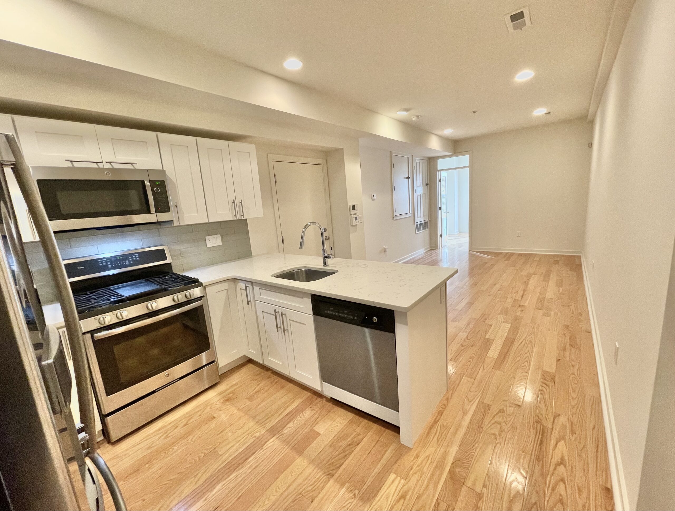 Modern Francisville condominium kitchen with quartz countertops, stainless steel appliances, hardwood floors, and open-concept layout